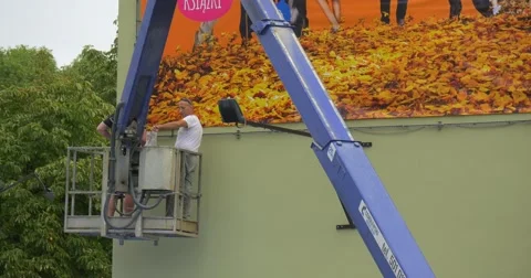 Two Men Workers in Truck Tower Are Installing an Orange Advertisement Banner Video stock 54839281