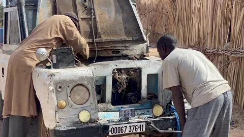 Two men working on the engine of a vintage white Land Rover vehicle outdoors in Stock Footage 342075767