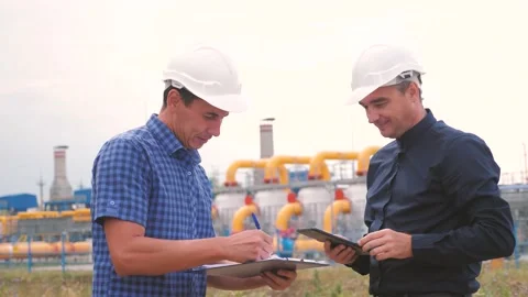 Two men working engineers work at a gas plant producing gas oil. industry Stock Footage 136459455