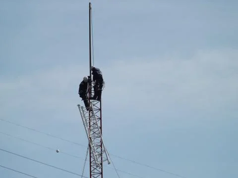 Two men working at height on a communications tower Stock Photos