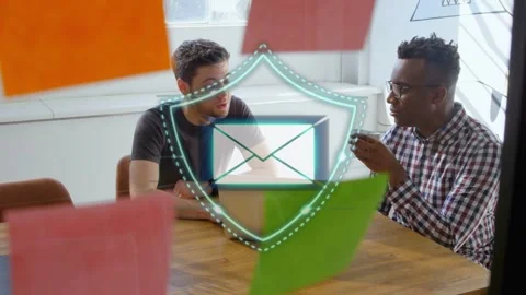 Two men working at laptop talking tech causing teal particles forming shield Stock Footage 335761730