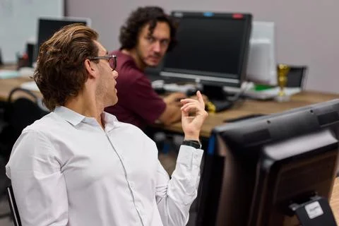 Two men working in an office collaborating on a computer task, in office Stockfoto's