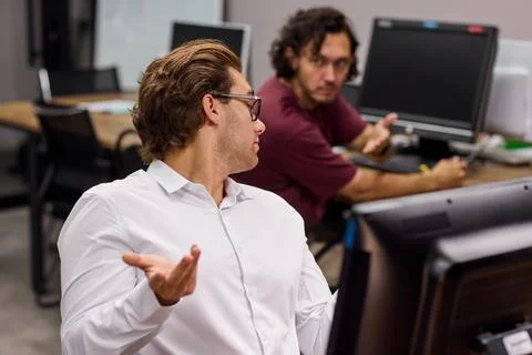 Two men working in an office collaborating on a computer task, in office Stockfoto's