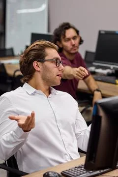 Two men working in an office collaborating on a computer task, in office Stockfoto's