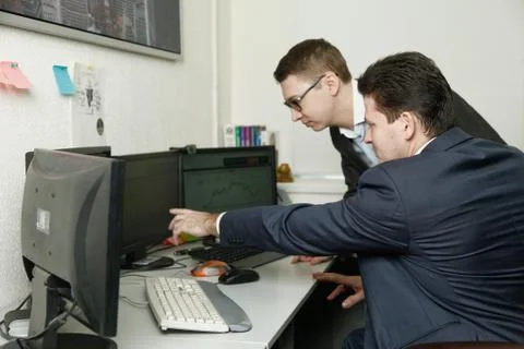 Two men working together for the computers in the office engaged in trading Stock Photos