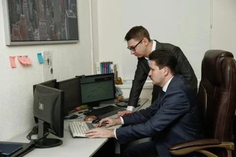 Two men working together for the computers in the office engaged in trading Stock Photos