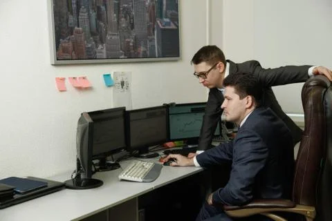 Two men working together for the computers in the office engaged in trading Stock Photos
