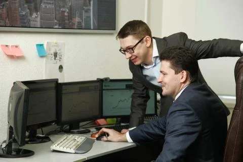 Two men working together for the computers in the office engaged in trading Stock Photos