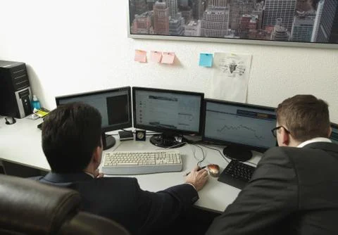 Two men working together for the computers in the office engaged in trading Stock Photos
