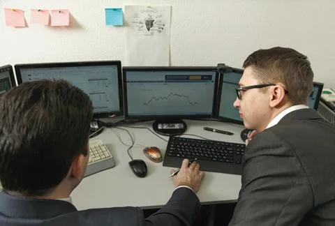 Two men working together for the computers in the office engaged in trading Stock Photos