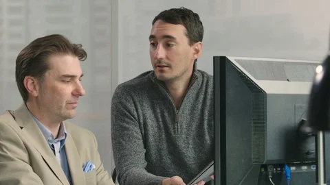 Two men working together in front of a computer screen Stock Footage 107732399