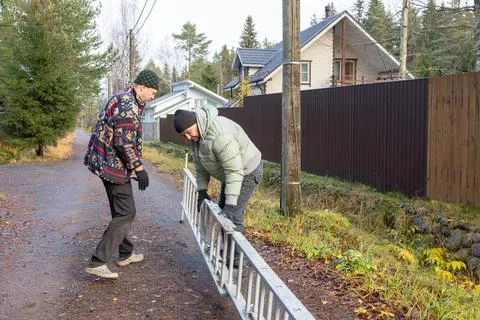 Two men working on utility pole with ladder on rural road Stock Photos