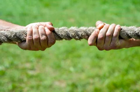 Two men's hands pull the rope each in his own direction. The concept of dispu Stock Photos