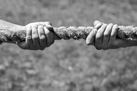 Two men's hands pull the rope each in his own direction. The concept of dispu Stock Photos