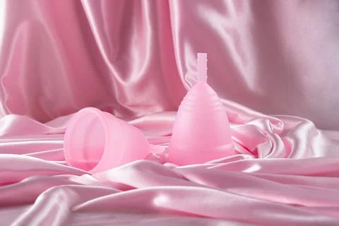 Two menstrual cups of different sizes made of medical silicone, against the b Stock Photos