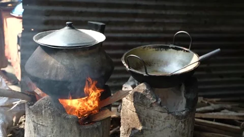 Two metal cooking pots on top of a burning fire on a clay farness Stock Footage 164553545