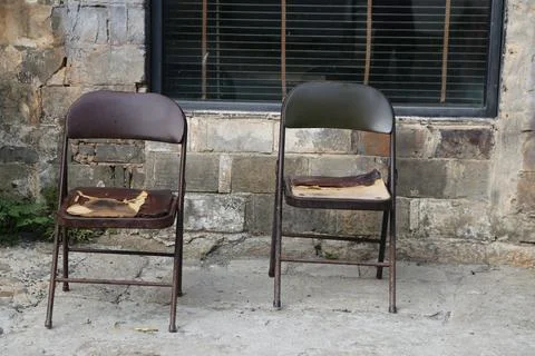 Two metal folding chairs with leather seats and backrests, both of them bro.. Stock Photos