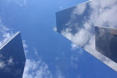 Two metal objects reflecting a blue sky with white clouds. Stock Photos