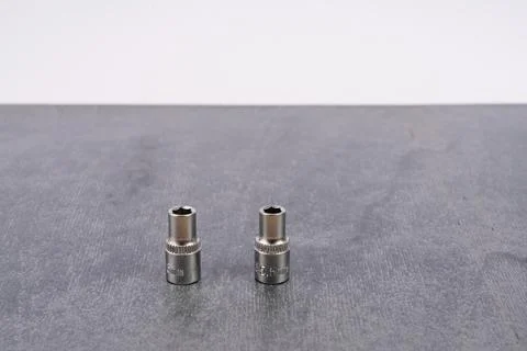 Two metal socket wrench attachments on gray surface Stock Photos