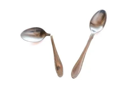 Two metal teaspoons - broken in half and serviceable on a white background. The Stock Photos