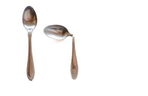 Two metal teaspoons - broken in half and serviceable on a white background. The Stock Photos