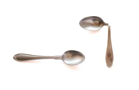 Two metal teaspoons - broken in half and serviceable on a white background. The Stock Photos