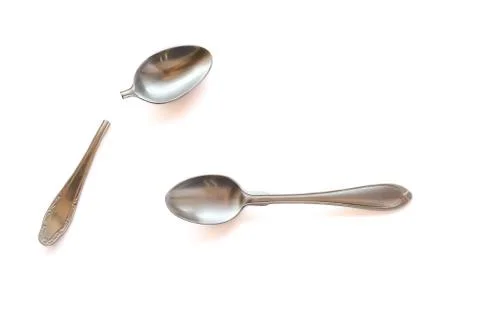 Two metal teaspoons - broken in half and serviceable on a white background. The Stock Photos