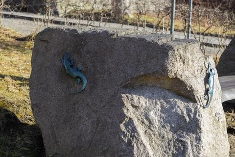 Two metallic lizard sculptures attached to a large rough granite stone in a Stock Photos