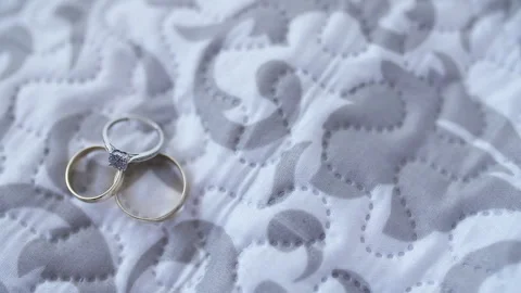 Two metallic rings resting on patterned quilted fabric Vidéo 336466818