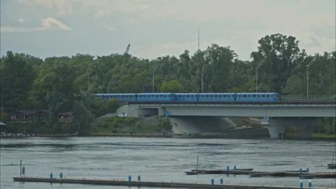 Two metro trains go in different directions on the bridge over the river Stock Footage 198382373