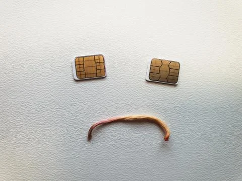 Two micro sim cards lying in the shape of a sad face Stock Photos
