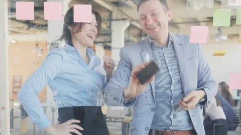 Two middle-aged managers, a man and a woman, work near a glass board, discuss Stock Footage 108985057