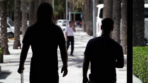 Two middle aged men walking through the outdoors of the airport while wearing 스톡 동영상 136393554