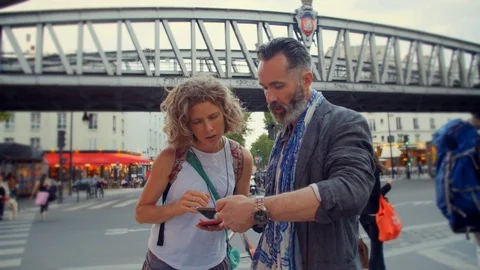 Two middle aged people looking at directions while out exploring Paris, France Stock Footage 120181555