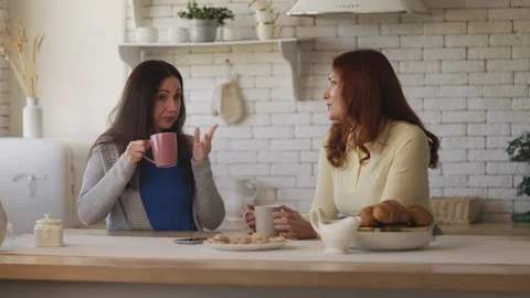 Two middle-aged women discussing the latest news while drinking tea together Stock Footage 337947227