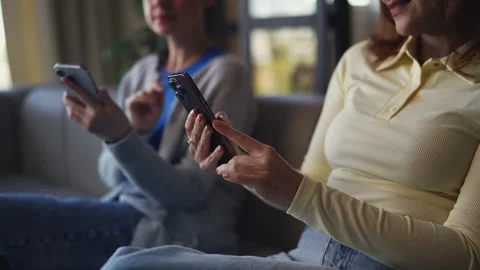 Two middle-aged women scrolling through social media on smartphones together Stock Footage 335960447