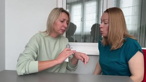 Two middle-aged women share skincare tips, demo product, beauty talk, trust. Stock Footage 308634982