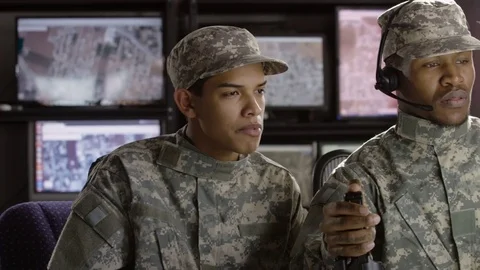Two military drone operators talking and watching computer screen, wide shot Stock Footage 70072862