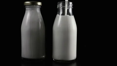 Two milk bottles on a black background. Slow motion Video stock 75269036
