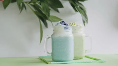 Two milkshakes blue and white stand on a green background. milkshakes on a white Stock-Footage 139886272