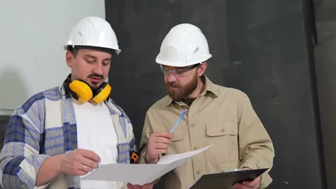Two millennial engineers discuss a drawing held by the construction supervisor Stock Footage 236762161