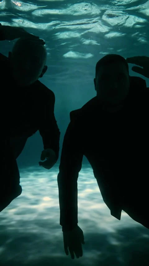 Two millennial men swim up to the side of the camera and look into the lens Stock Footage 315560149