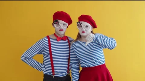 Two mimes are playing a funny performance on a yellow background. A couple of Stock Footage 223645344