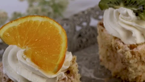Two mini fruit-topped cakes with whipped cream, garnished with orange Video stock 308923079