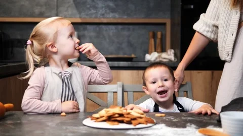 Two mischievous children getting caught in the act while sneaking cookies from Stock Footage 291615453