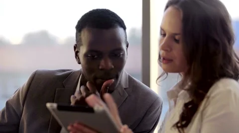 Two mixed collegues working with tablet. They discussing business ideas sitting Видео 68686649