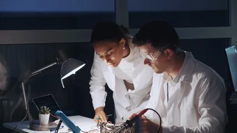 Two mixed race electronics engineers working with multimeter tester and other Stock Footage 112875296