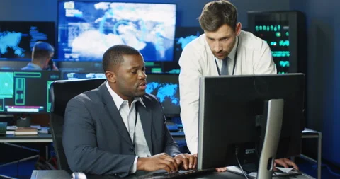 Two mixed-races males data security analytics talking and working at computer in Stock Footage 139236329