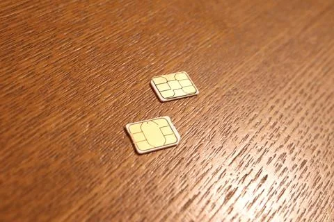Two mobile phone SIM cards with golden electronic chips lying on a textured.. Stock Photos