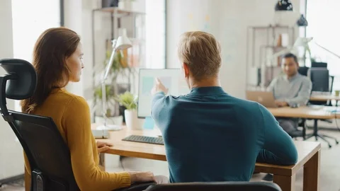 Two Mobile Software Developers Work on Desktop Computer, They Discuss Smartphone Stock Footage 112600654